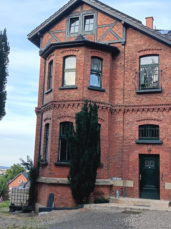 a red brick house with a tree in front of it at Ferienwohnung Harzteufel in Blankenburg
