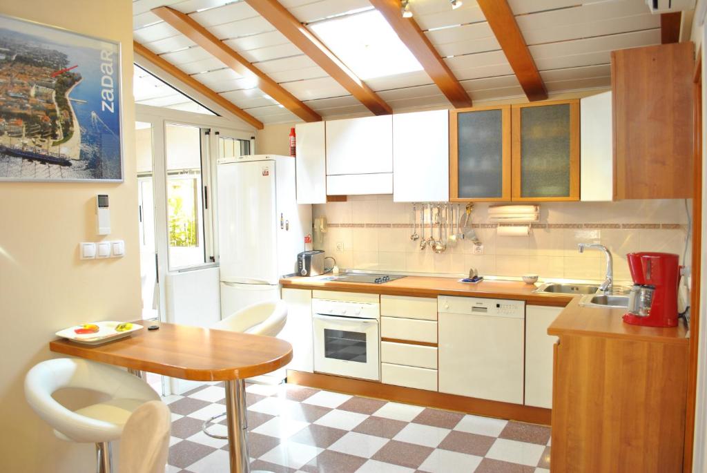 een keuken met witte kasten, een tafel en een wastafel bij Apartment Eva in Zadar