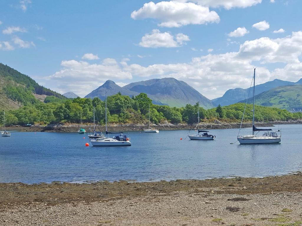 a group of boats on a lake with mountains in the background at Lismore Cottage in North Ballachulish