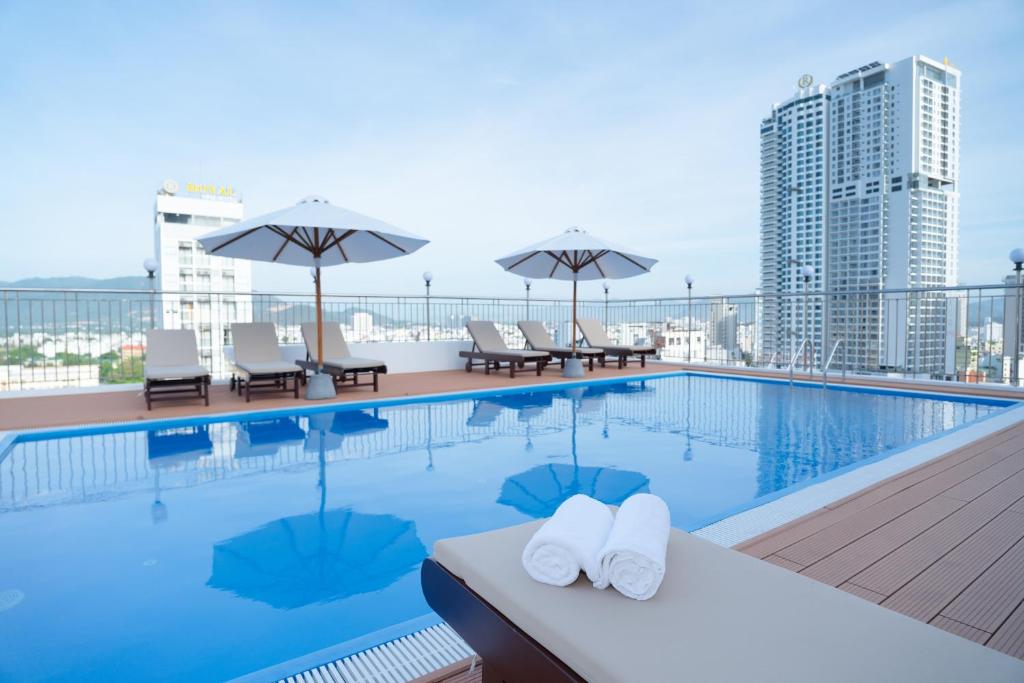 a swimming pool with chairs and umbrellas on a building at Galliot Hotel Nha Trang in Nha Trang