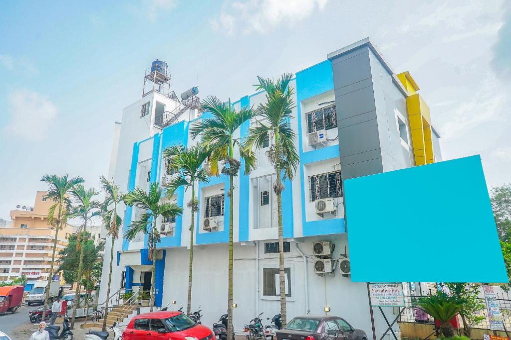 プネにあるHotel O Paradise Inn Talegaon Dabhadeの前にヤシの木がある建物