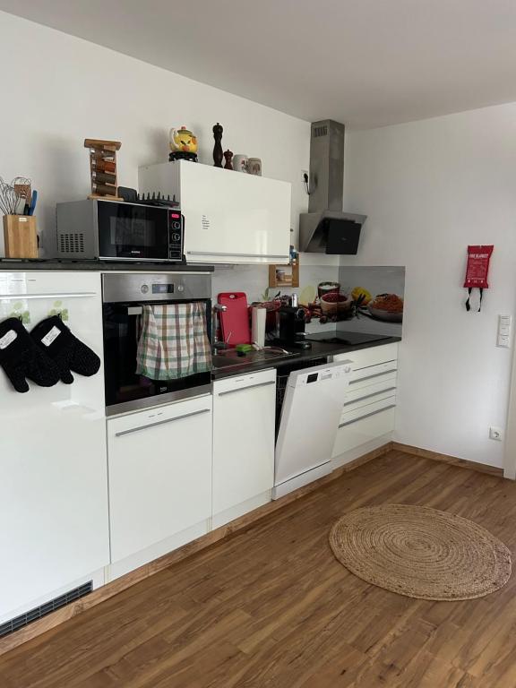 a kitchen with white appliances and a wooden floor at Charmantes Feriennest vor Seßlachs Stadtmauer im lebendigen Familienhaus in Seßlach