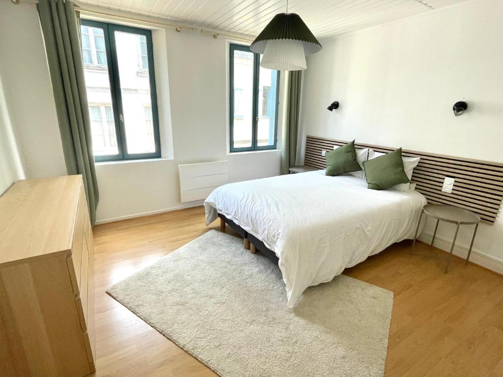 une chambre avec un grand lit blanc avec des oreillers verts dans l'établissement La Belle Picarde, centre Saint Valery sur Somme, à Saint-Valery-sur-Somme