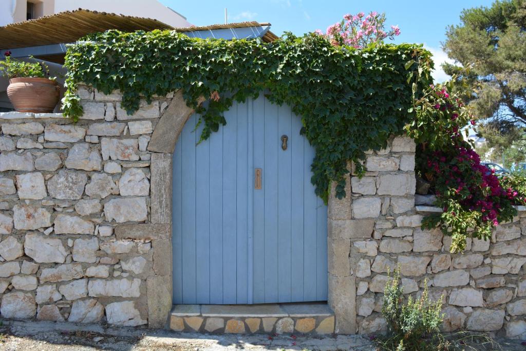 a blue door in a stone wall with flowers at Volta Stonehouse Apartments in Frátsia