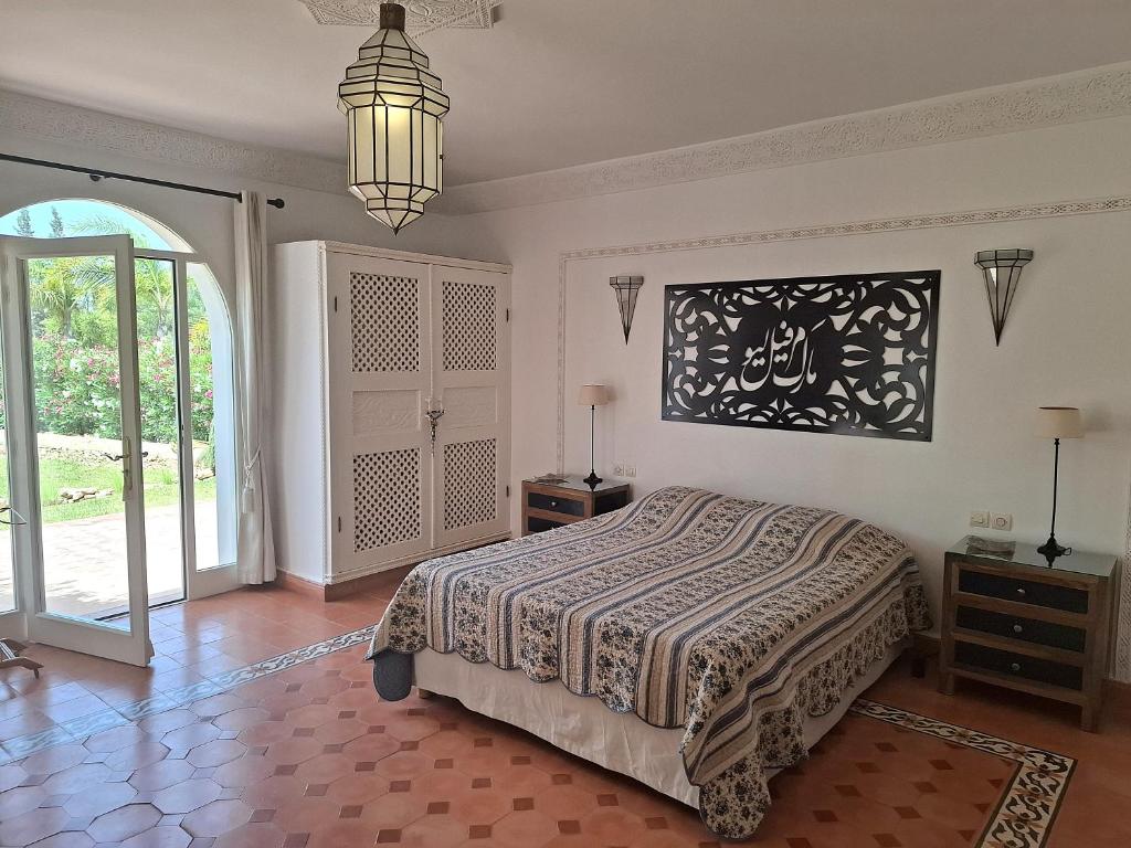 - une chambre avec un lit et une lampe pendant dans l'établissement Magnifique villa piscine Ghazoua, à Al Ghar