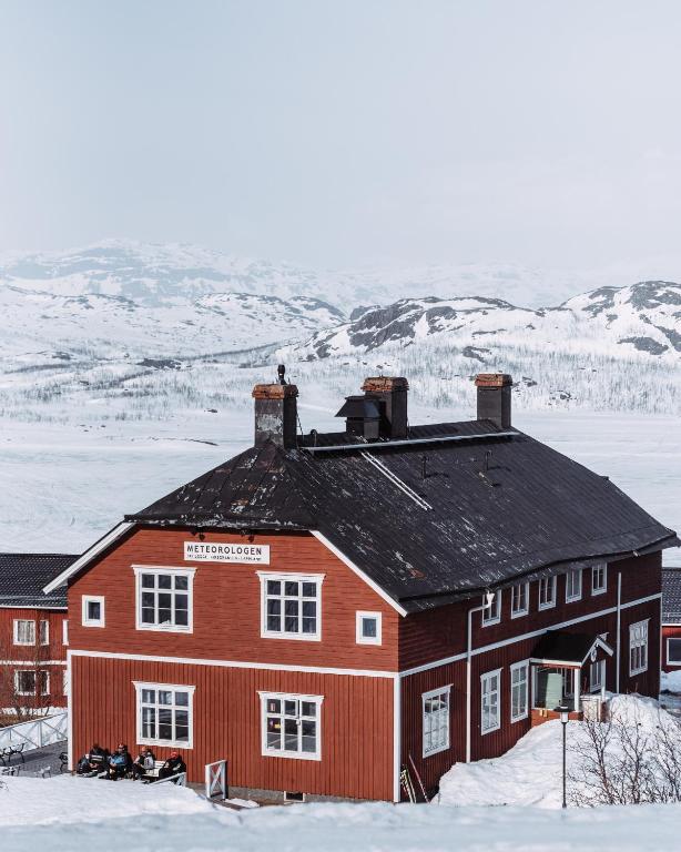 a red barn in the snow with snow covered mountains at Meteorologen Ski Lodge in Riksgränsen
