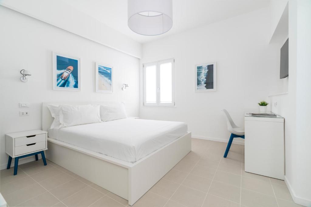a white bedroom with a white bed and a chair at Puolo Seaside Apartment 3 in Massa Lubrense