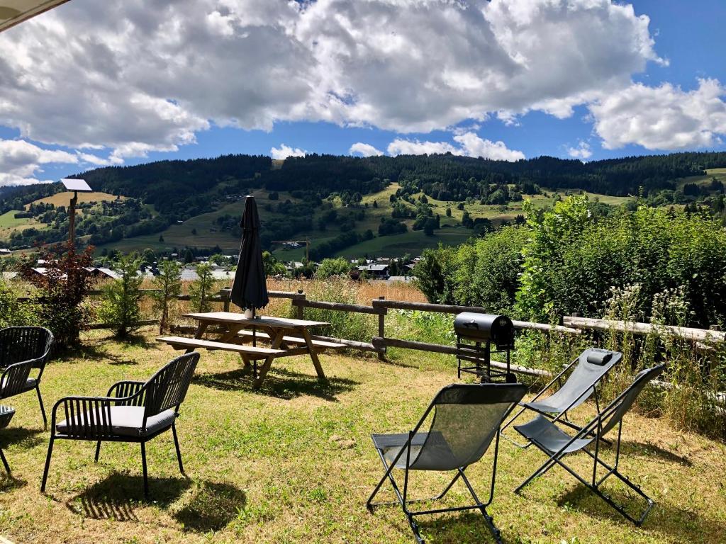 a group of chairs and a picnic table and a umbrella at Le Chalet 138 Megève séjour pour 8 confort espace charme calme in Demi-Quartier