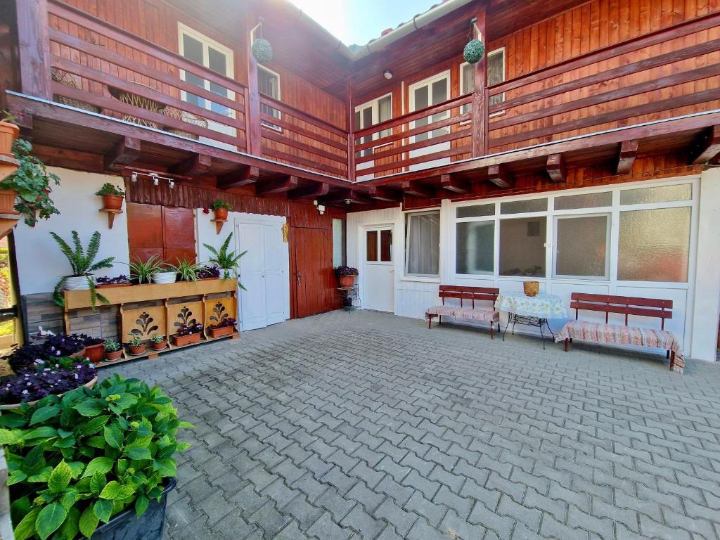an outdoor patio with benches and a porch at Casa Rica Vendégház in Sovata
