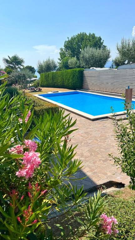 a swimming pool in a yard with pink flowers at Bardolino Blue in Bardolino