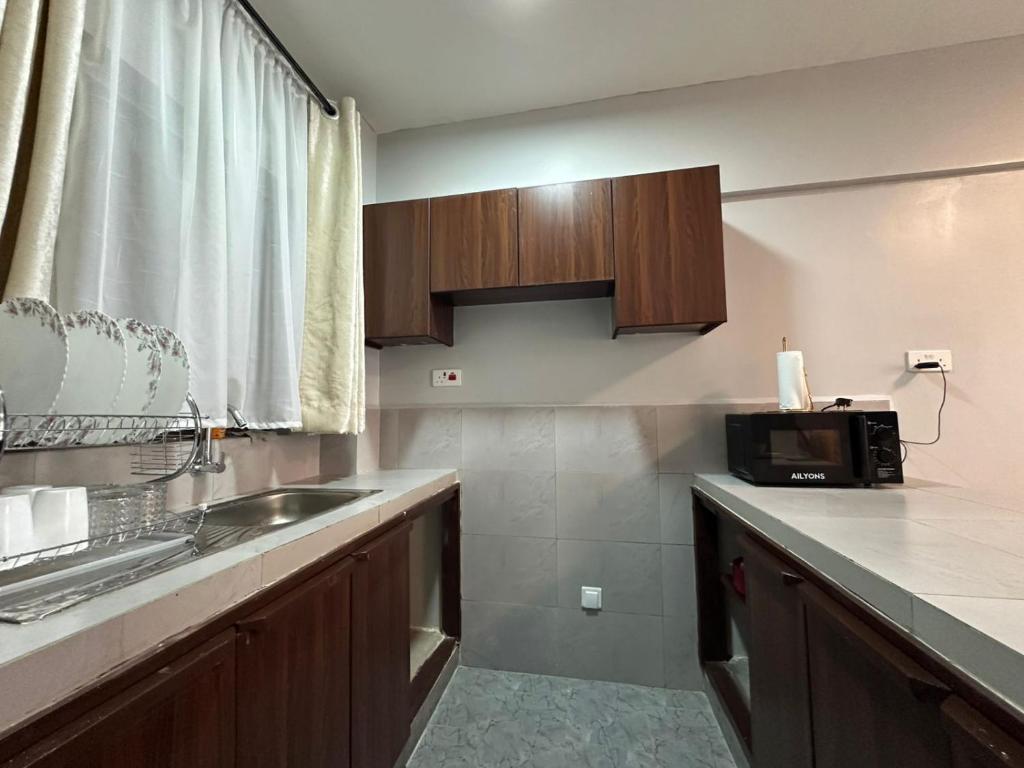 eine Küche mit Spüle und Mikrowelle in der Unterkunft Akombe homestay-Makasembo in Kisumu