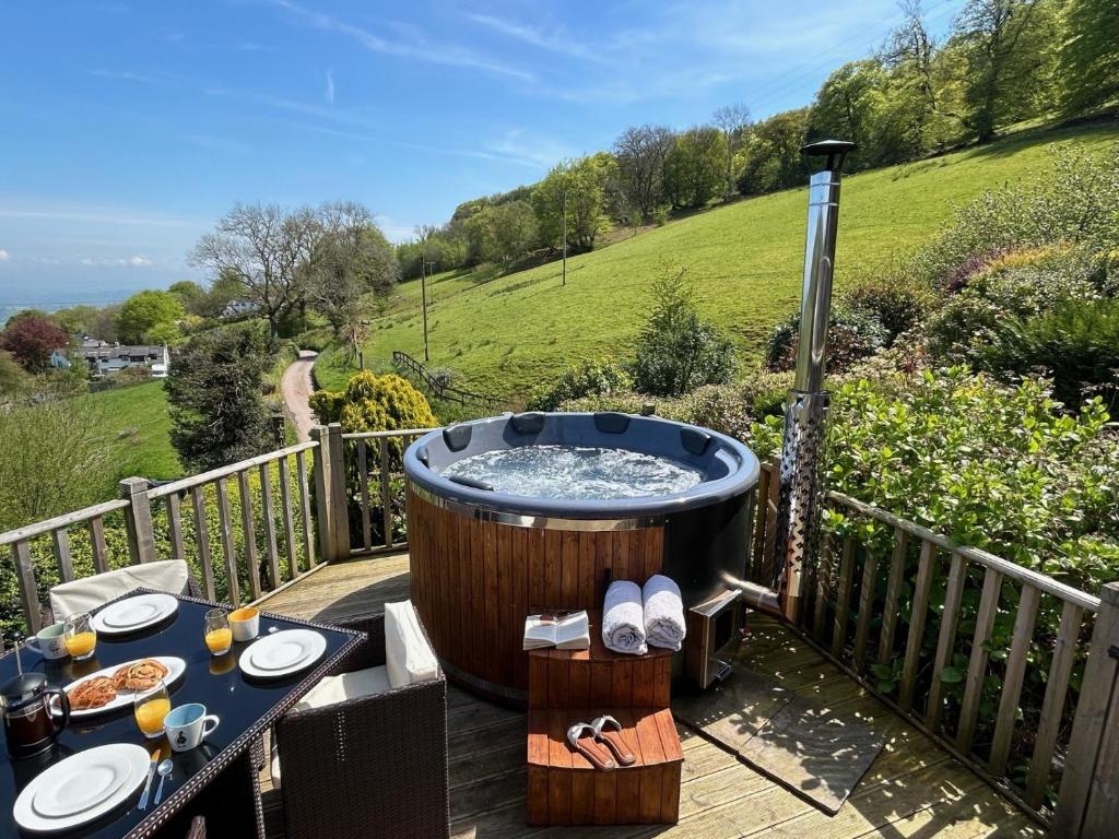 a hot tub on a wooden deck with a table with food at 2 Bed in Abergavenny 83894 in Llanover