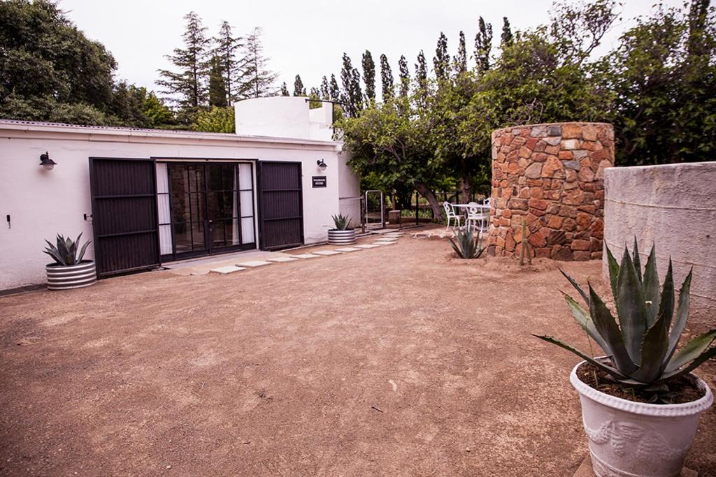 a house with a yard with a stone wall at Vygeboom Studio in Nieu-Bethesda