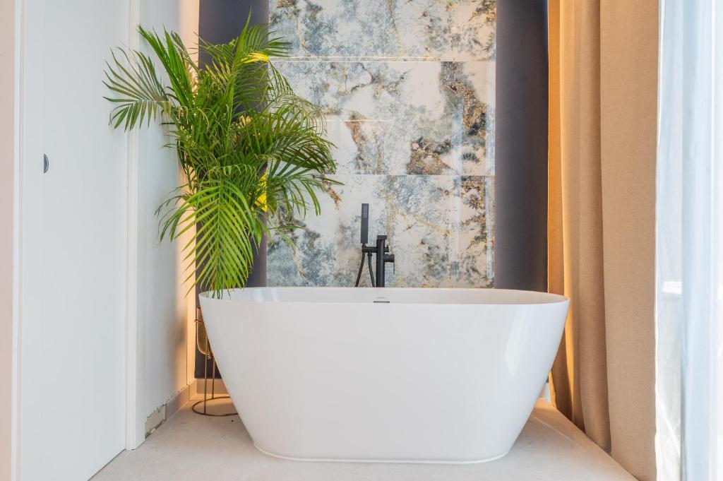 a white bath tub in a bathroom with a plant at Samstag ParkZone in Split