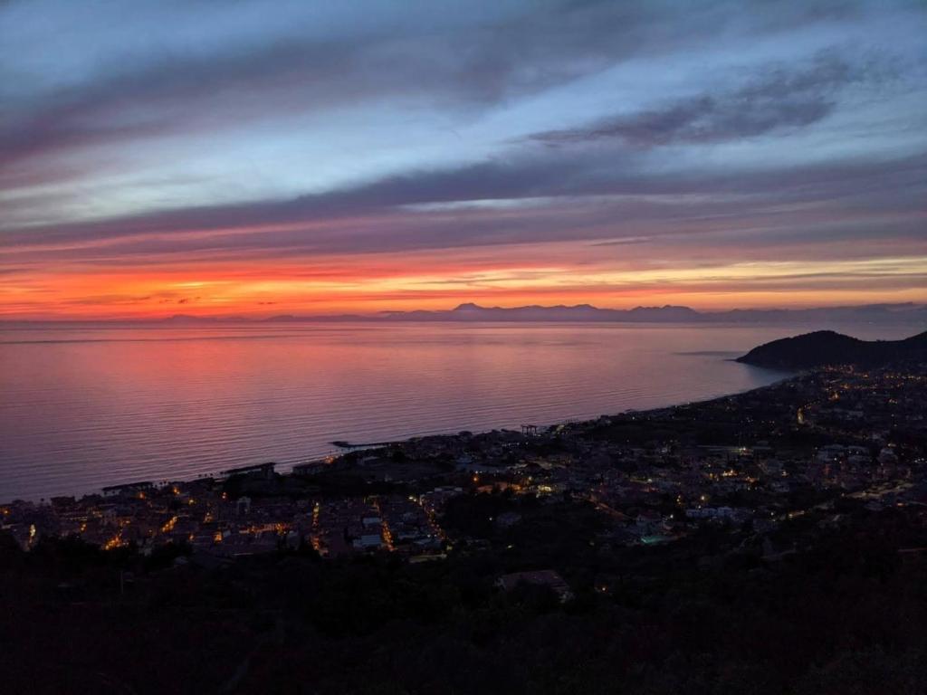 a sunset over the water with a city and the ocean at Attico vista mare con terrazza panoramica in Castellabate
