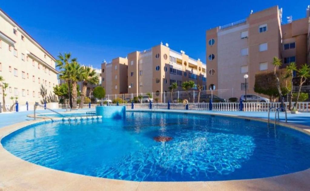 Una gran piscina azul con edificios al fondo. en Beau et paisible T4 torrevieja, en Torrevieja