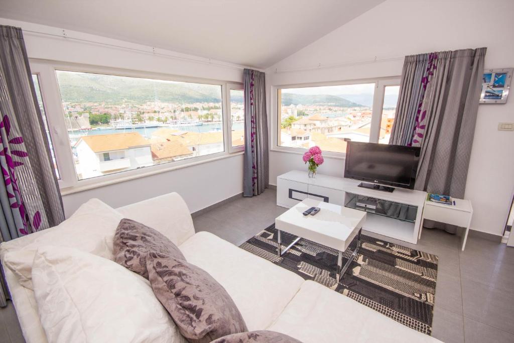 a living room with a white couch and a tv at Apartments Maria in Trogir