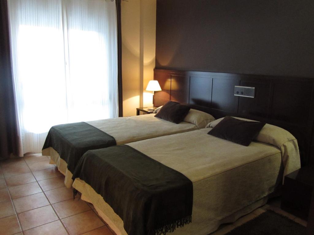 a bedroom with two beds and a large window at Hotel Villa de Utrillas in Utrillas