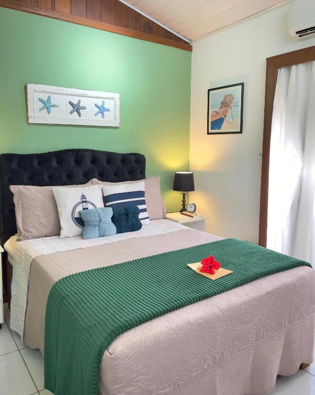 a bedroom with a large bed with a green blanket at 1QuartoPra2 Centro Búzios in Búzios