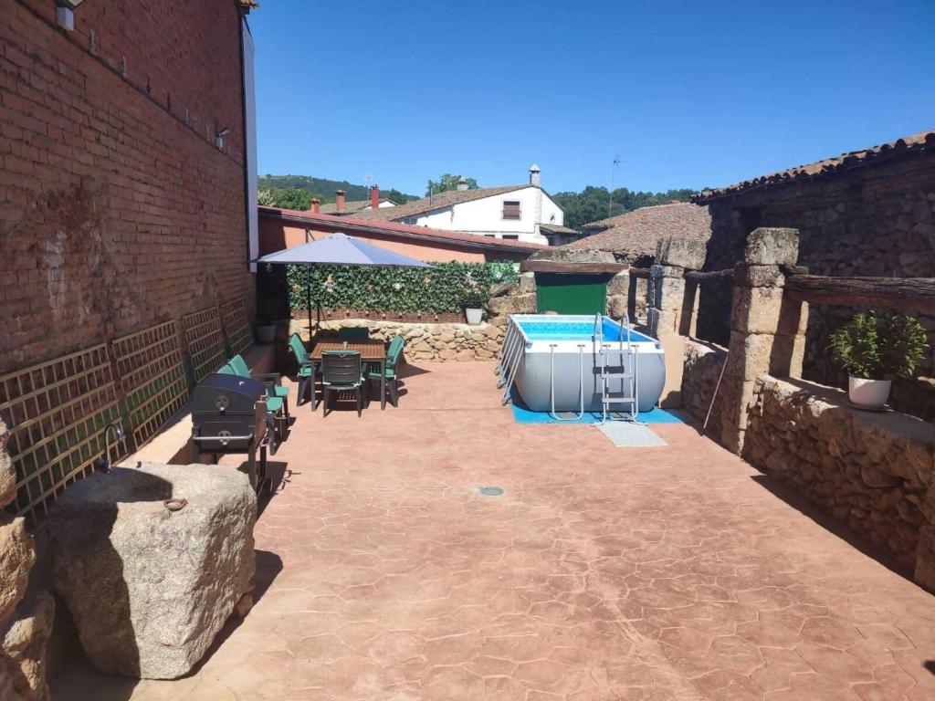a patio with a hot tub and tables and chairs at Casa rural Regajo Lobos in San Bartolomé de Béjar