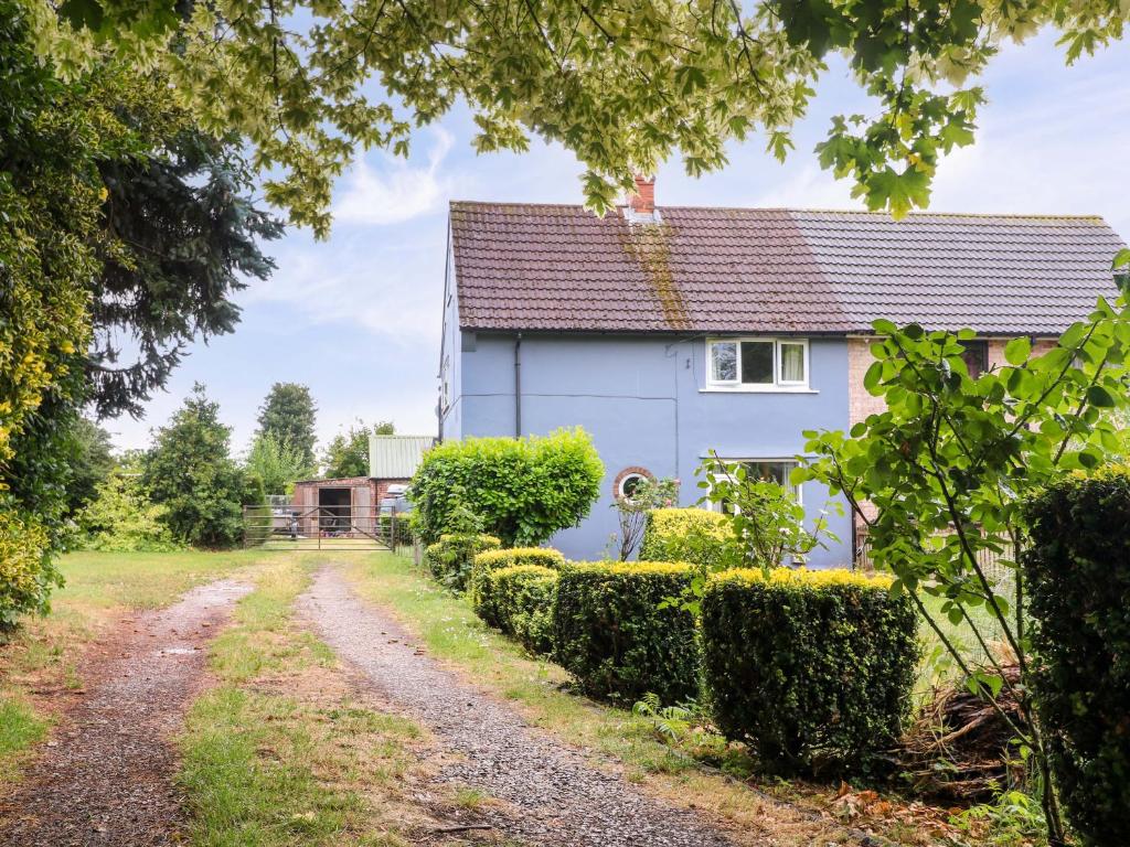 a white house with hedges next to a dirt road at Oxcroft View in Worksop