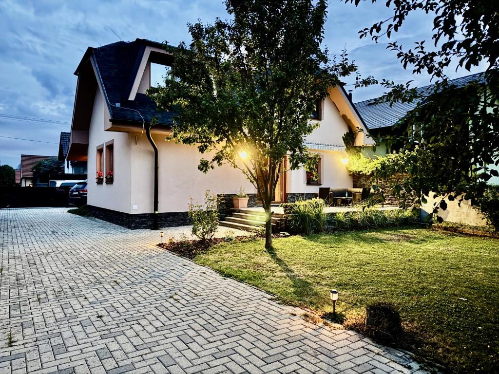 a house with a tree and a brick driveway at Terchovský dvor - Ubytovanie & wellness in Terchová