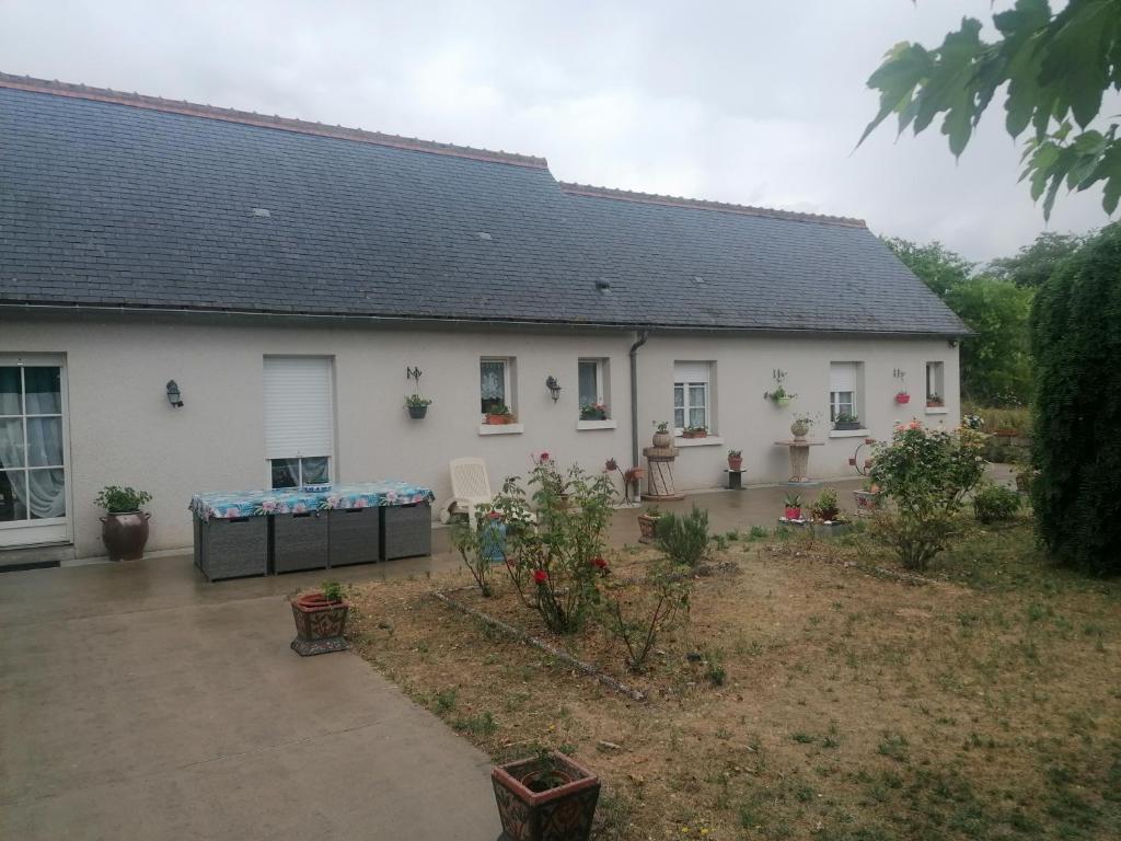 une maison blanche avec un jardin en face dans l'établissement Le Clos des roses, à Civray-de-Touraine