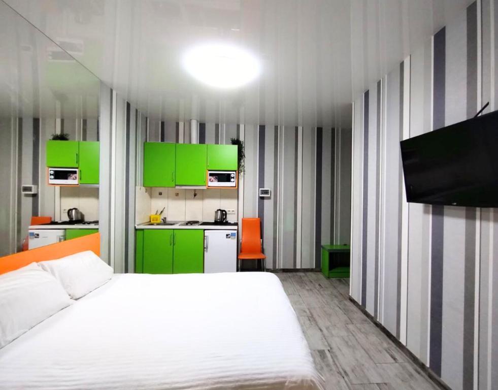 1 dormitorio con 1 cama blanca y armarios verdes en Безпечні апартаменти на цокольному поверсі біля метро, en Járkov