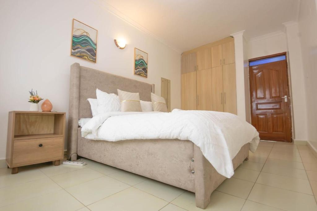 - une chambre avec un grand lit et une armoire en bois dans l'établissement Serene Spaces Garden Estate, à Gatunga