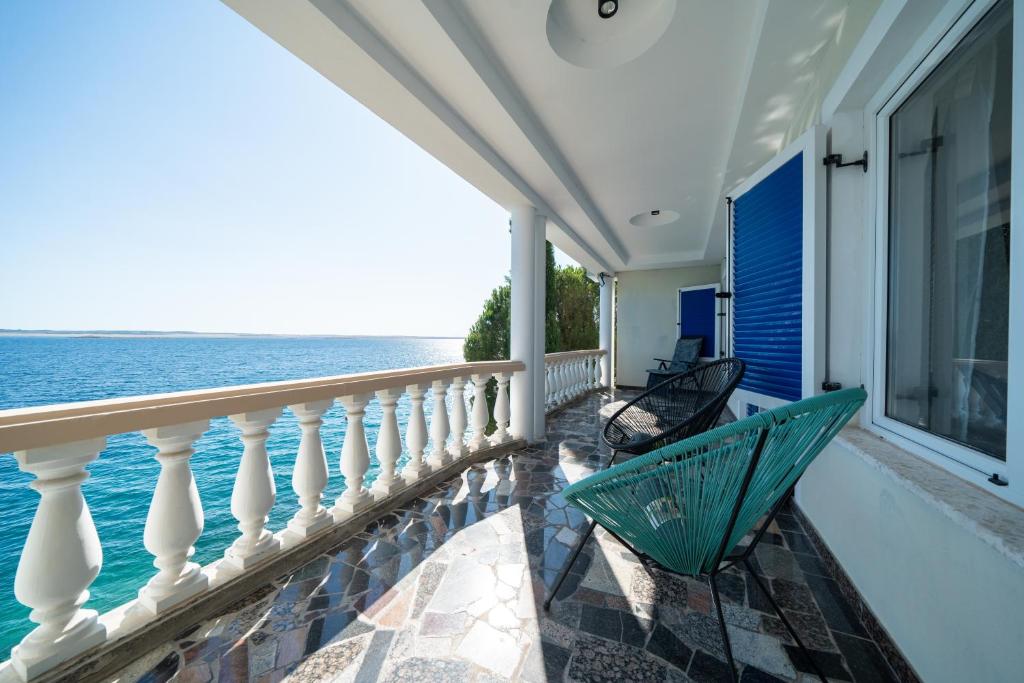 a balcony with two chairs and the ocean at Holiday home SeVeN - Barefoot by the Sea, Velebit, Nature in Starigrad-Paklenica