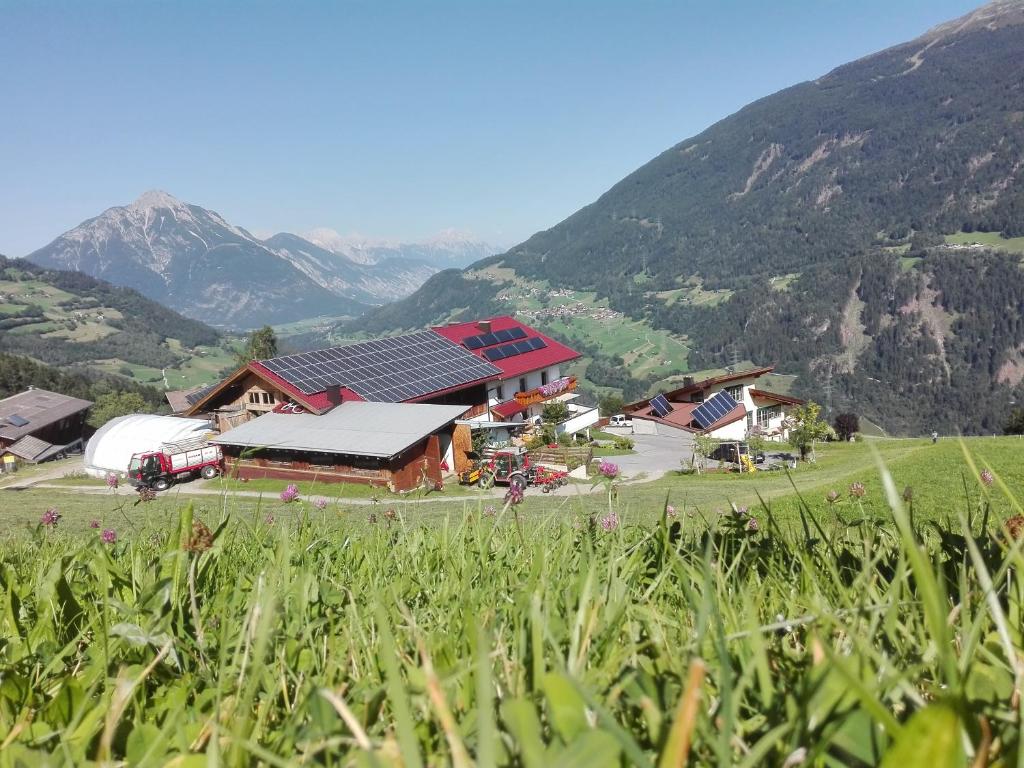 uma quinta com um celeiro com montanhas ao fundo em Ferienwohnung Berghof Pixner em Wenns