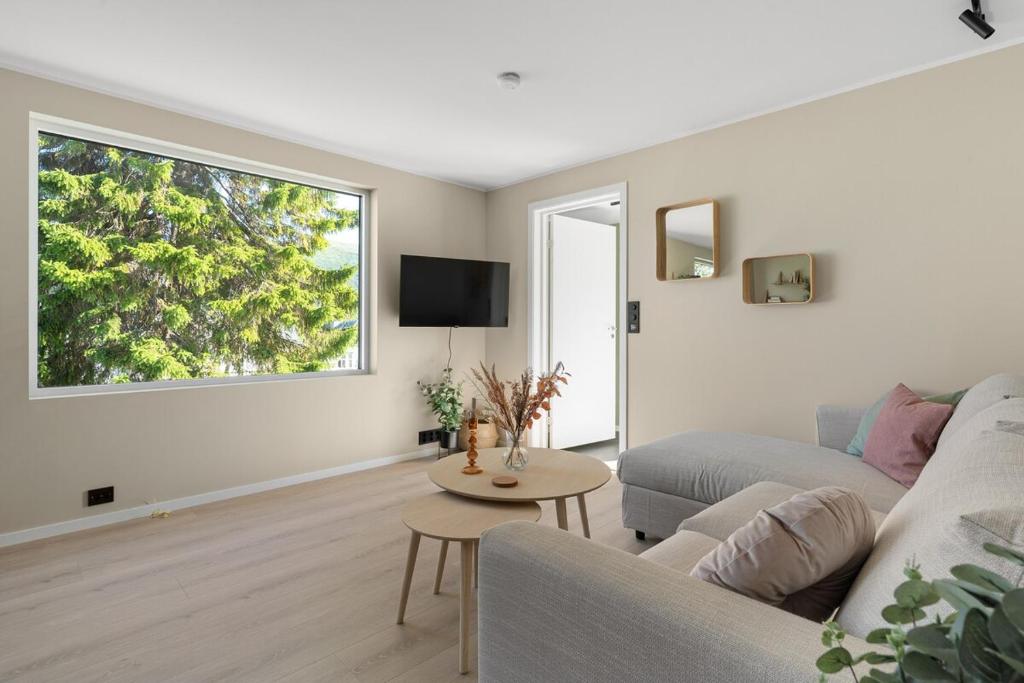 ein Wohnzimmer mit Couch und großem Fenster in der Unterkunft Northstay - Tromsø Urban Retreat - Free Parking, Brand New & Modern in Tromsø