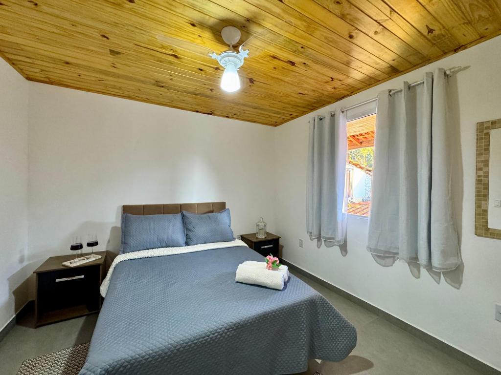 a bedroom with a blue bed with a wooden ceiling at Casa Paiol de Visconde de Mauá in Resende