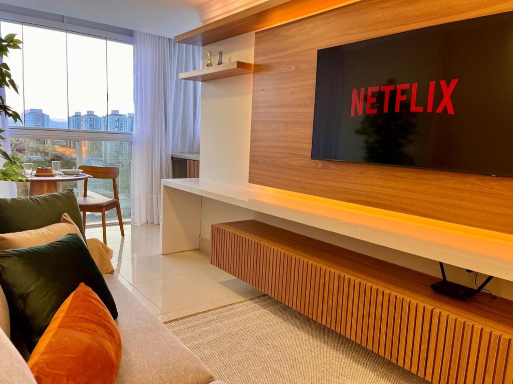 a living room with a television on a wall at PRAIA Mar Sofisticado Novo in Vila Velha