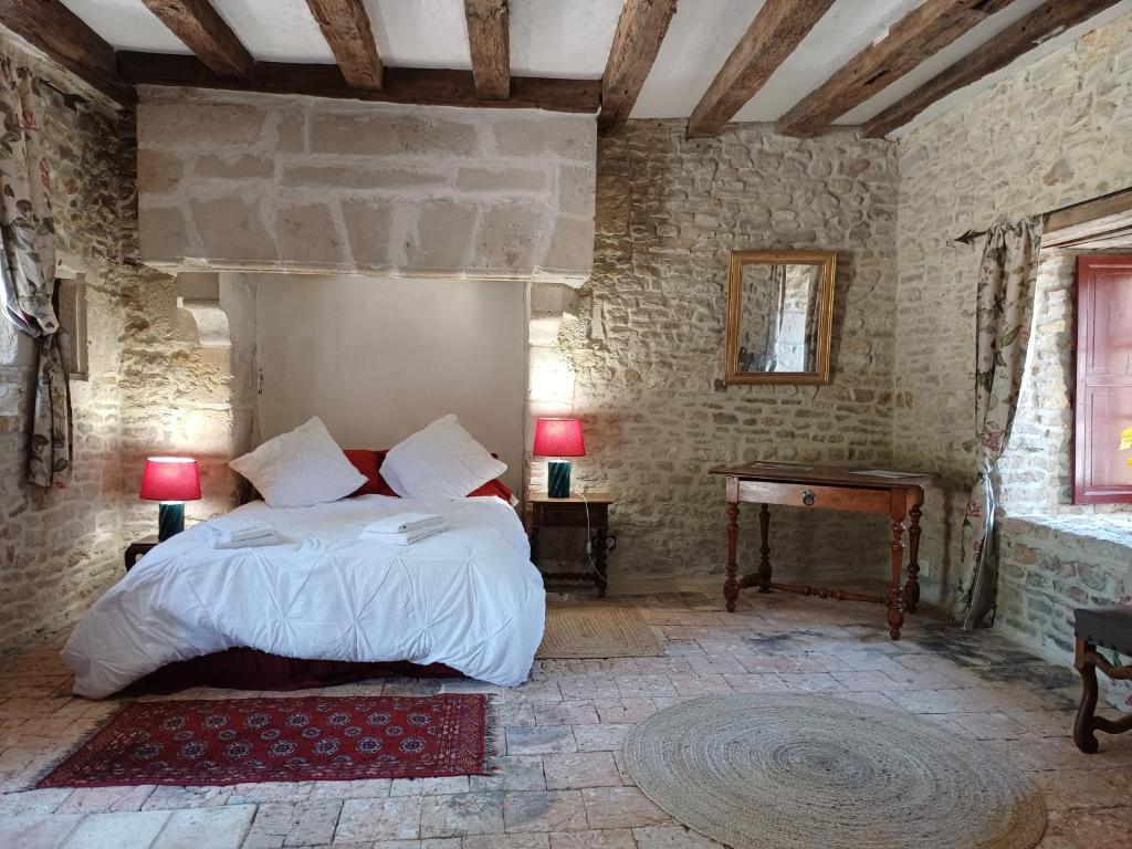 a bedroom with a bed and a table in a room at Chambre entrée indépendante dans tour du 15ème siècle in Mauvières