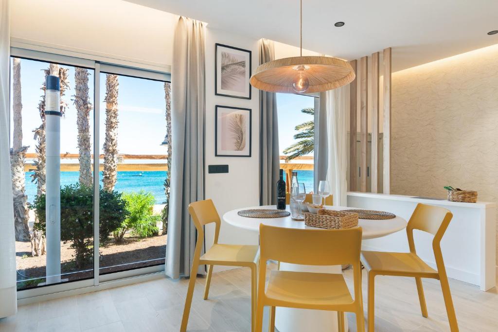 Un comedor con mesa y sillas y una gran ventana. en Home2Book Stylish Beachfront Escape, en Arinaga