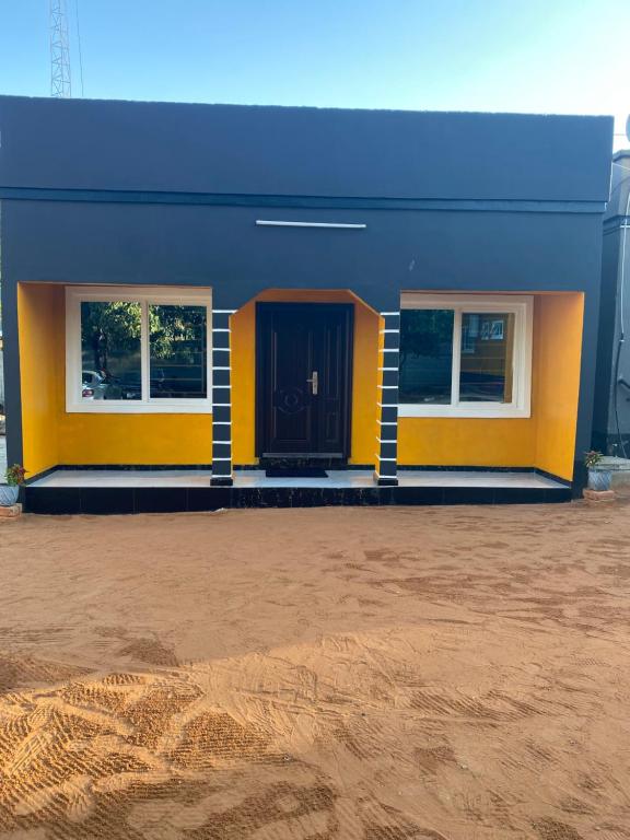 a blue and yellow building with a black door at Ramachi Apartment A in Livingstone