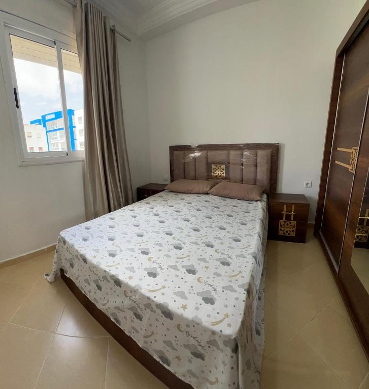 a bedroom with a bed in a room with a window at Appartement À Martil in Martil