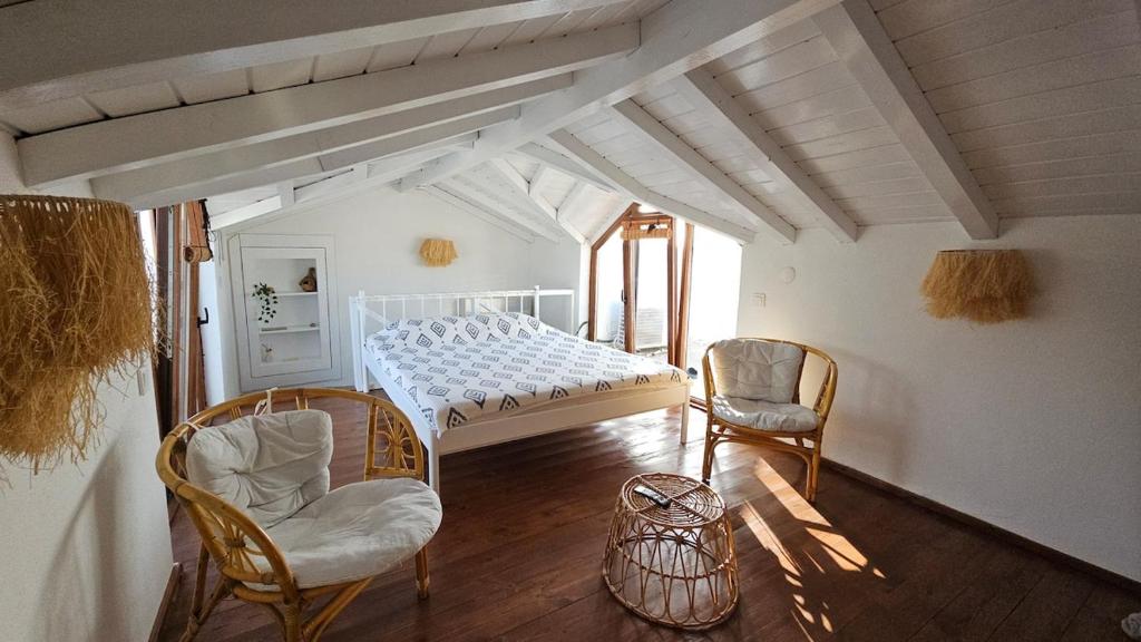 Un dormitorio con una cama blanca y dos sillas. en Villa Toscana, en Gökçeada