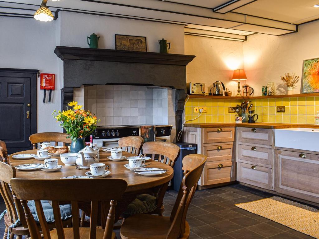 cocina con mesa con sillas y chimenea en Needle House, en Ravenstonedale