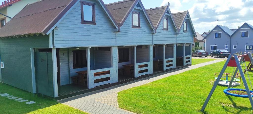 a large blue house with windows and a playground at Domki Bursztynowa Zatoka 2 in Sarbinowo
