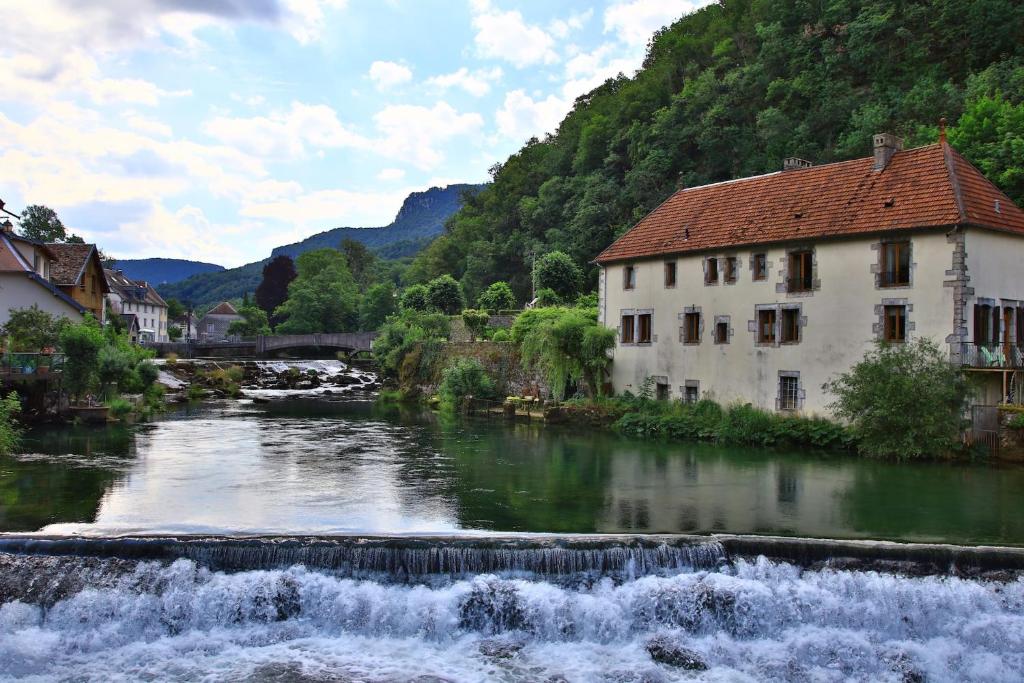 a river with a building next to a waterfall at Au fil de Lods in Lods