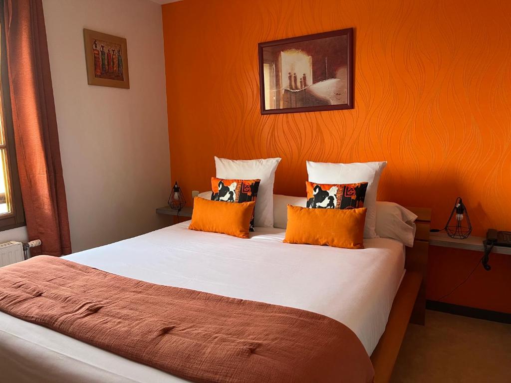 a bedroom with a large bed with orange walls at Logis hôtel Les Confins du perche in Sceaux-sur-Huisne