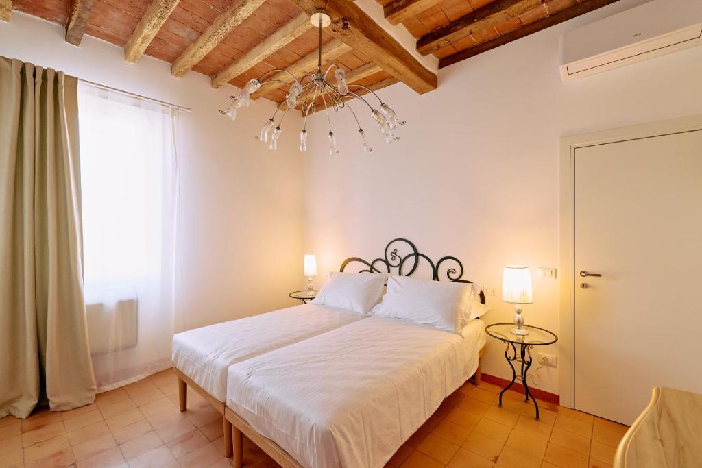a bedroom with a white bed and a chandelier at Casa Lippa in Spilamberto