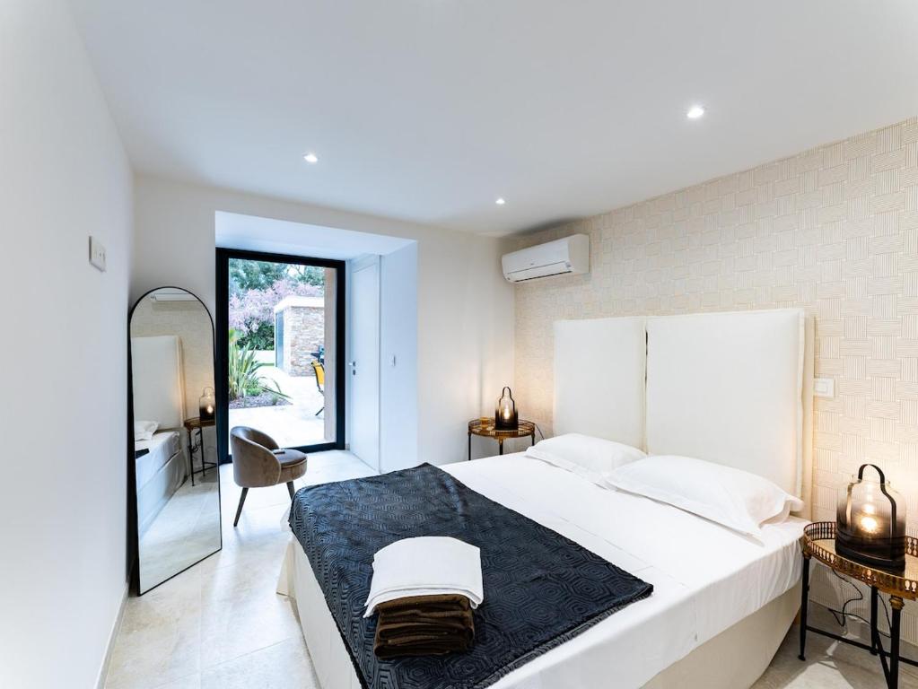a white bedroom with a large bed and a mirror at Appart HOTEL 3 Chambres - parking - clim in Saint-Raphaël