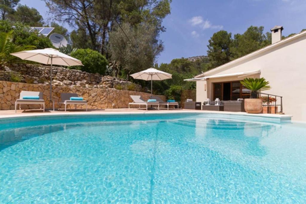 une grande piscine avec chaises et parasols dans l'établissement Exclusive Palma Villa with Modern Amenities, 1001, à Calvià