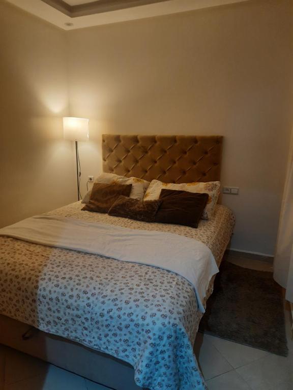 a bedroom with a large bed with a lamp at Séjour Idéal à Tamaris Appartement Meublé Tout Confort in Tamaris
