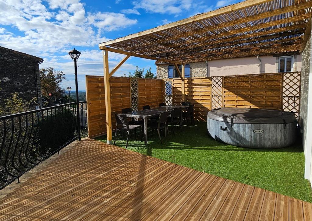 une terrasse en bois avec un grill, une table et un grill dans l'établissement Appartement et son jacuzzi, à Saint-Cézaire-sur-Siagne