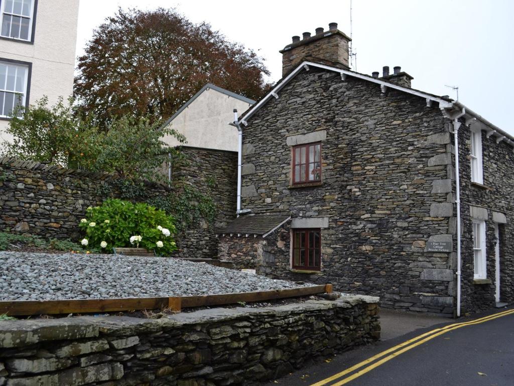una casa de piedra al lado de una carretera en Pear Tree Cottage, en Bowness-on-Windermere