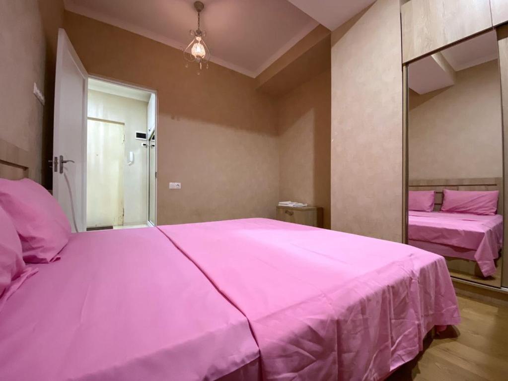 - un grand lit rose dans une chambre avec un miroir dans l'établissement ბინა საბურთალოზე 2 საძინებელი #17, à Tbilissi